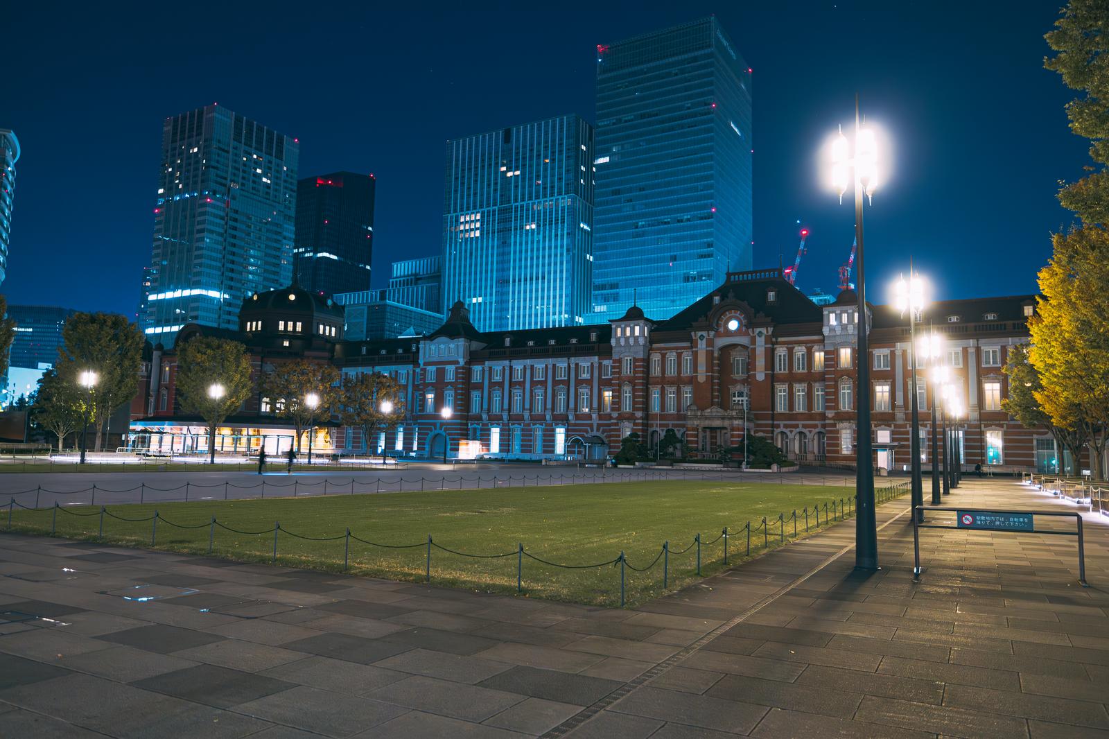 夜明け前に照らされた東京駅舎と背後の高層ビル群の夜景