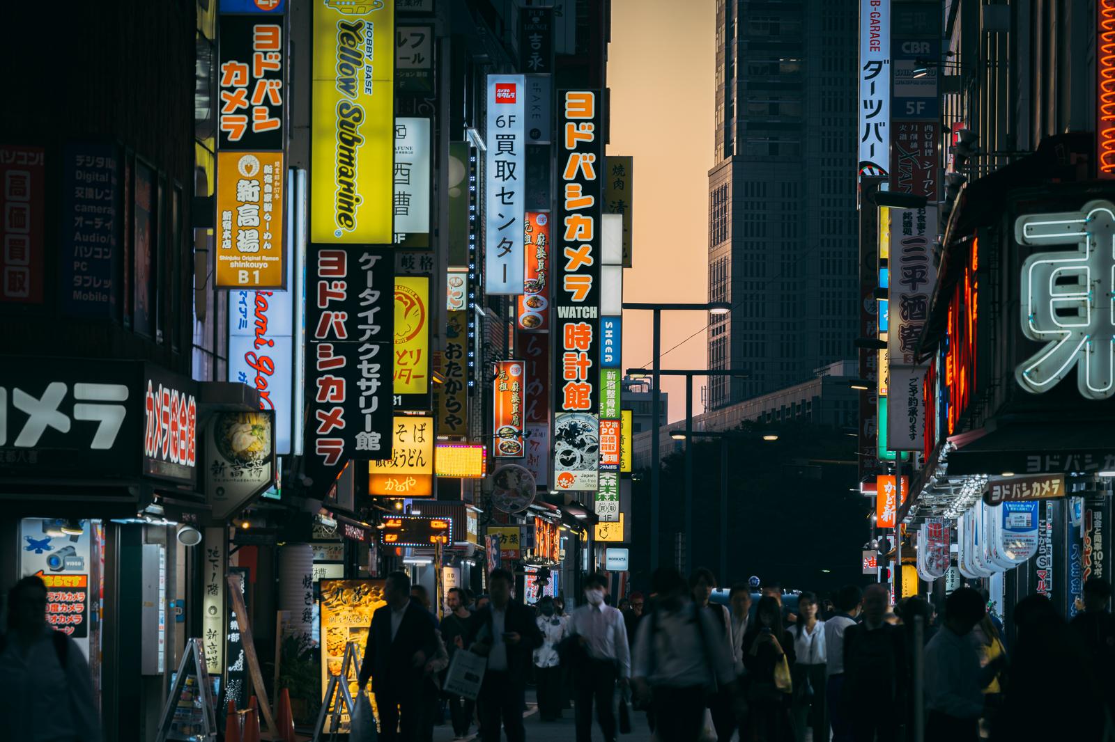 新宿西口の繁華街で光る看板と歩く人々の夜景