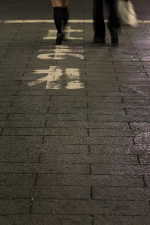 止まれの標識の前に立つヒール姿の女性の足元