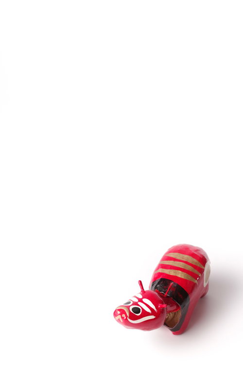 白い背景にぽつんと置かれた赤べこ、干支の牛をモチーフにした郷土玩具