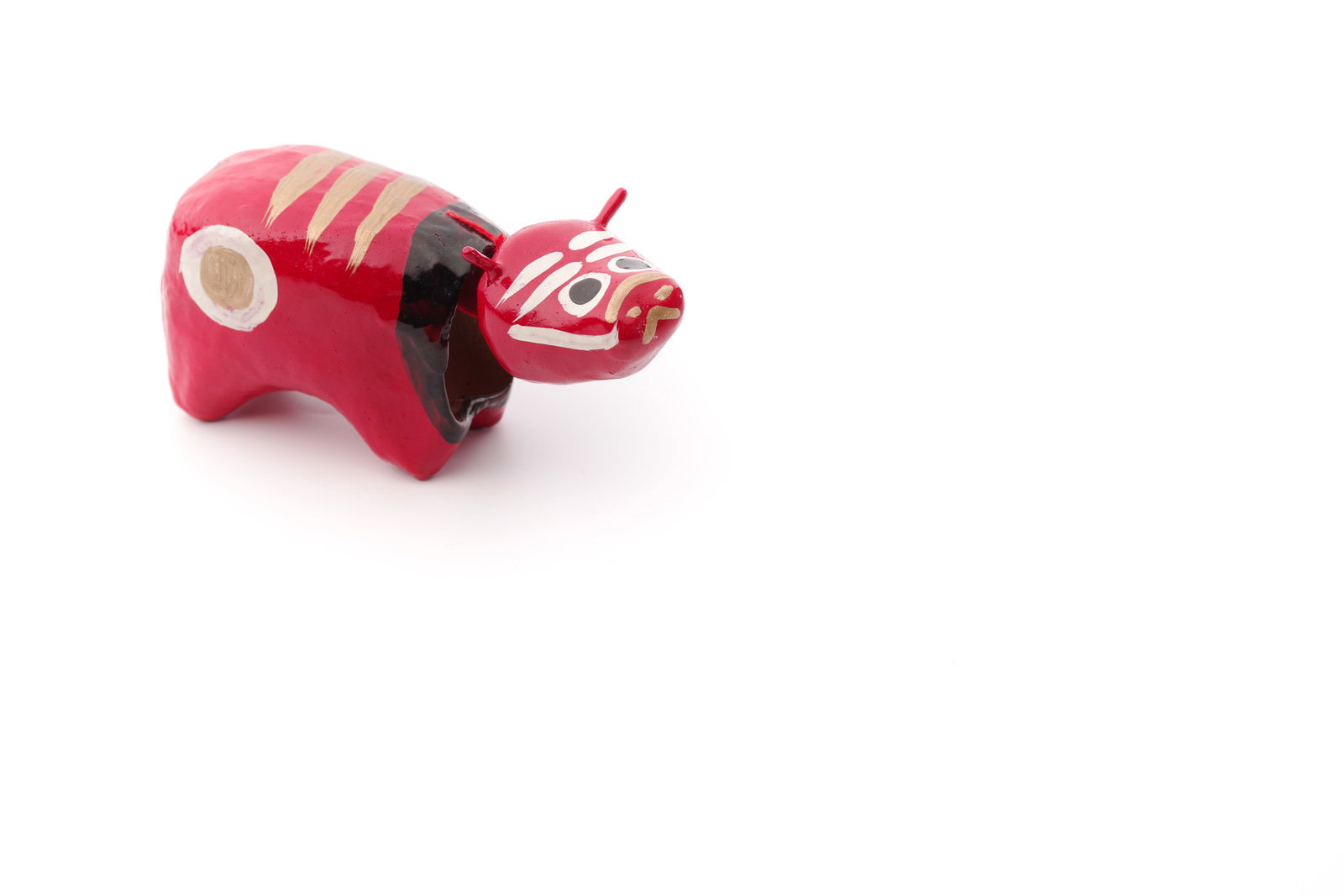 白い背景に置かれた赤い色の赤べこの置物