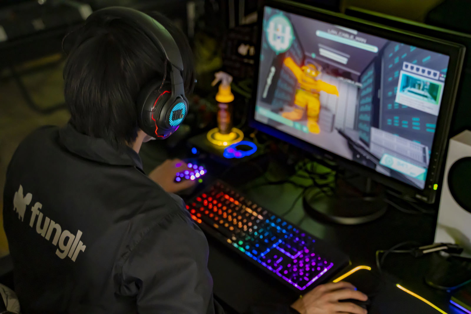 ヘッドセットを装着してFPSゲームをプレイするゲーマーがモニター前でキーボードを操作している