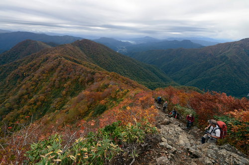 紅葉する谷川岳の稜線を歩く登山者の秋景色