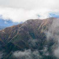 雲がかかる谷川連峰の秋の紅葉風景の写真