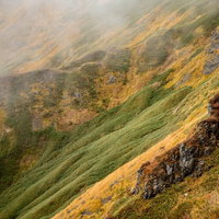 霧が駆る秋の谷川岳の紅葉した山肌の写真