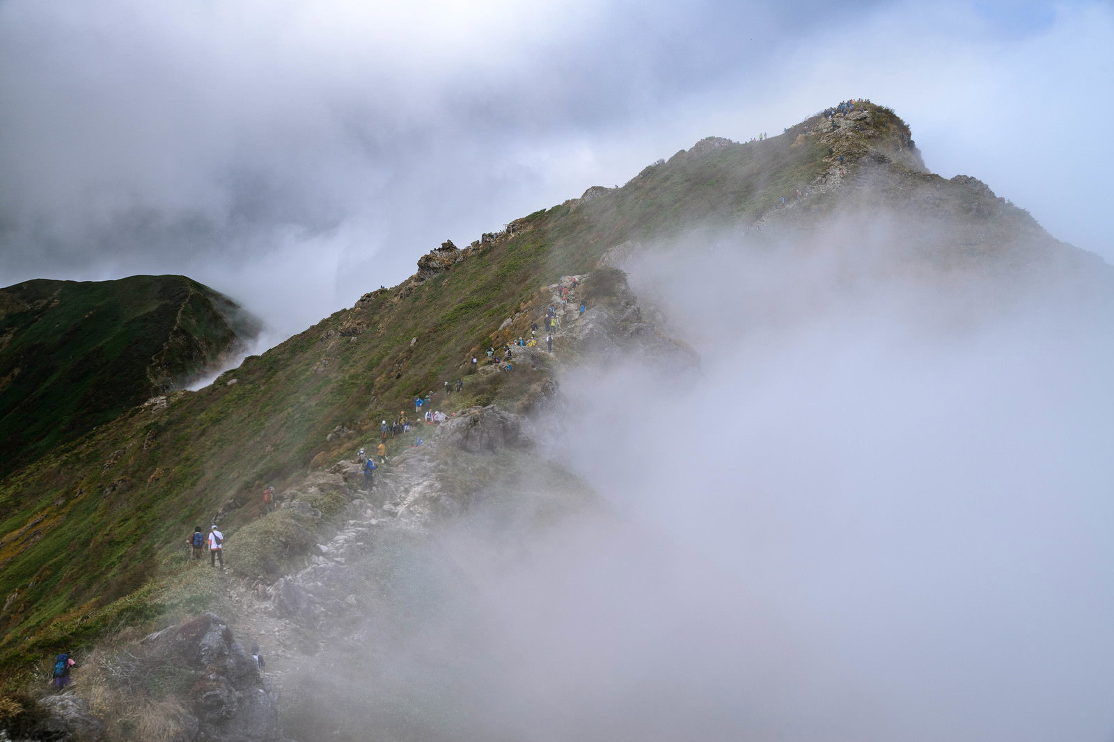 雲海に包まれた谷川岳の尾根で休憩する登山者達の山岳風景