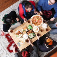 テーブルの上でピザなどを食べながらパーティーしている家族団らんの写真