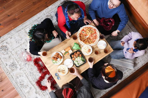 テーブルの上でピザなどを食べながらパーティーしている家族団らん