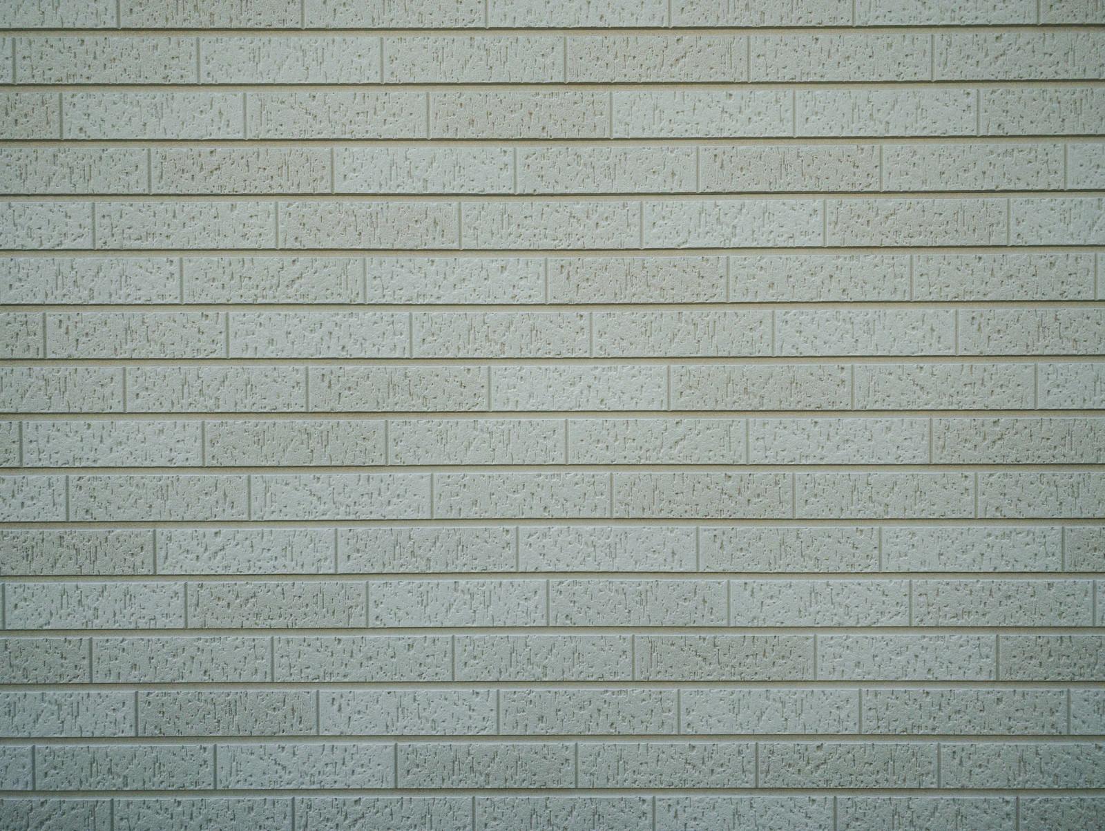 薄いグレー色で小さな凹模様が施されたタイル壁のテクスチャー