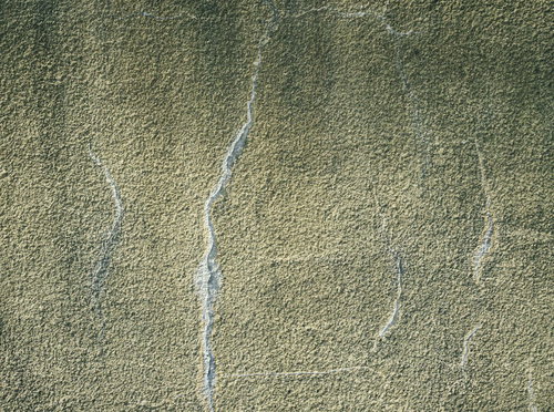 白い亀裂の入った黄色いコンクリート壁のテクスチャー