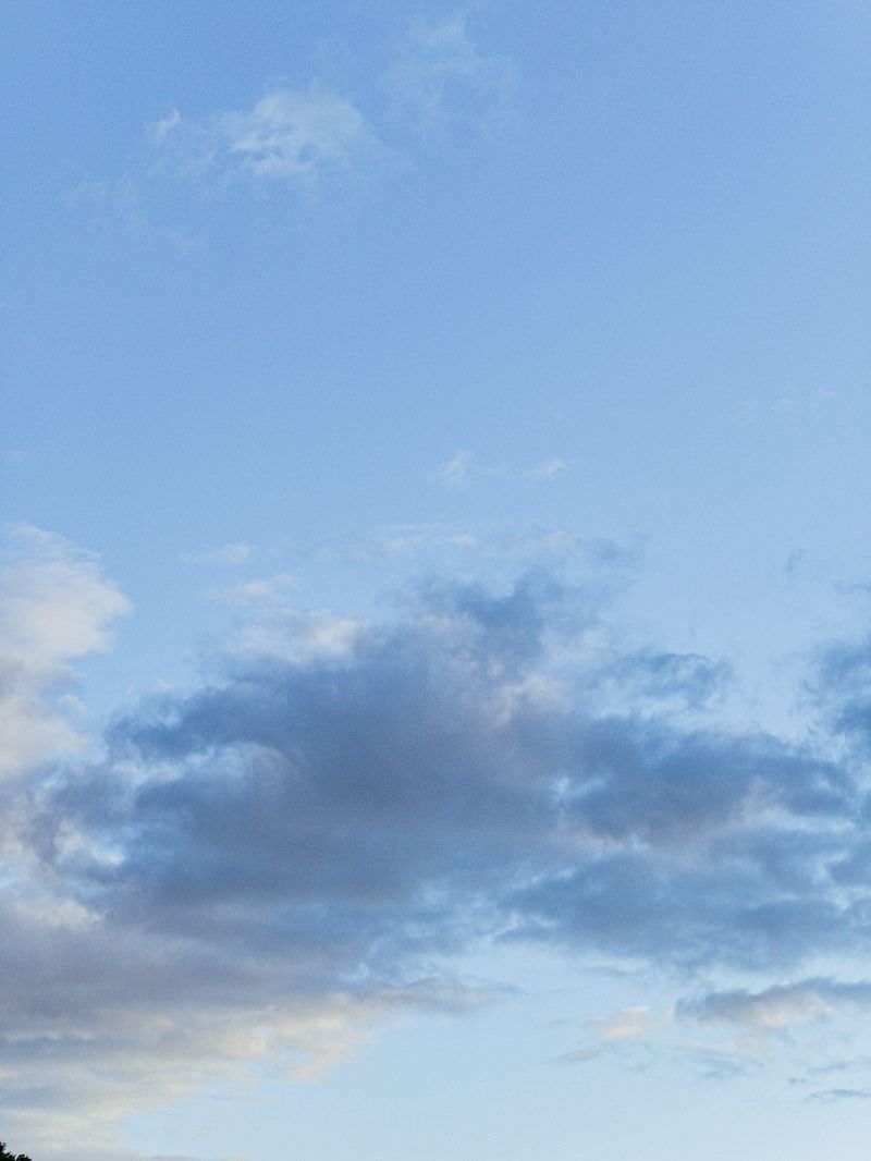 青空に白い雲がゆったりと浮かんでいる穏やかな空の風景