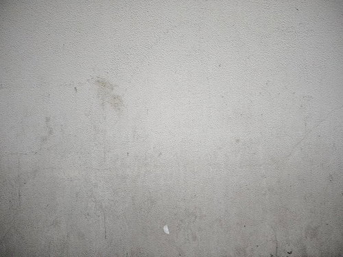 経年劣化で汚れたグレーのモルタル壁のテクスチャー