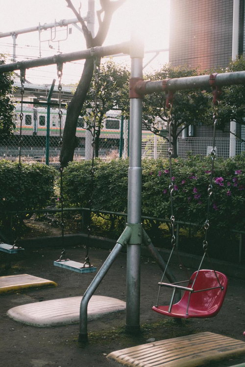 台東区立鶯谷公園のブランコと電車が見える線路風景