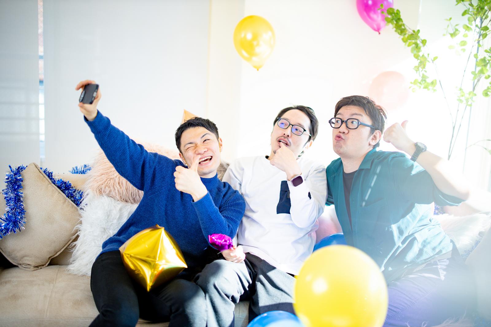 ホームパーティー中にスマートフォンで自撮りをする3人の男性グループ［モデル：OZPA ゆうせい モデルリリース］