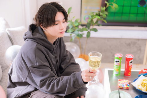 推しの彼とホームパーティーを過ごす、グレーのパーカー姿でくつろぐ男性