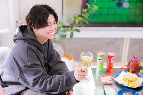 グレーパーカーの男性がシャンパンで乾杯、記念日パーティーを楽しむ