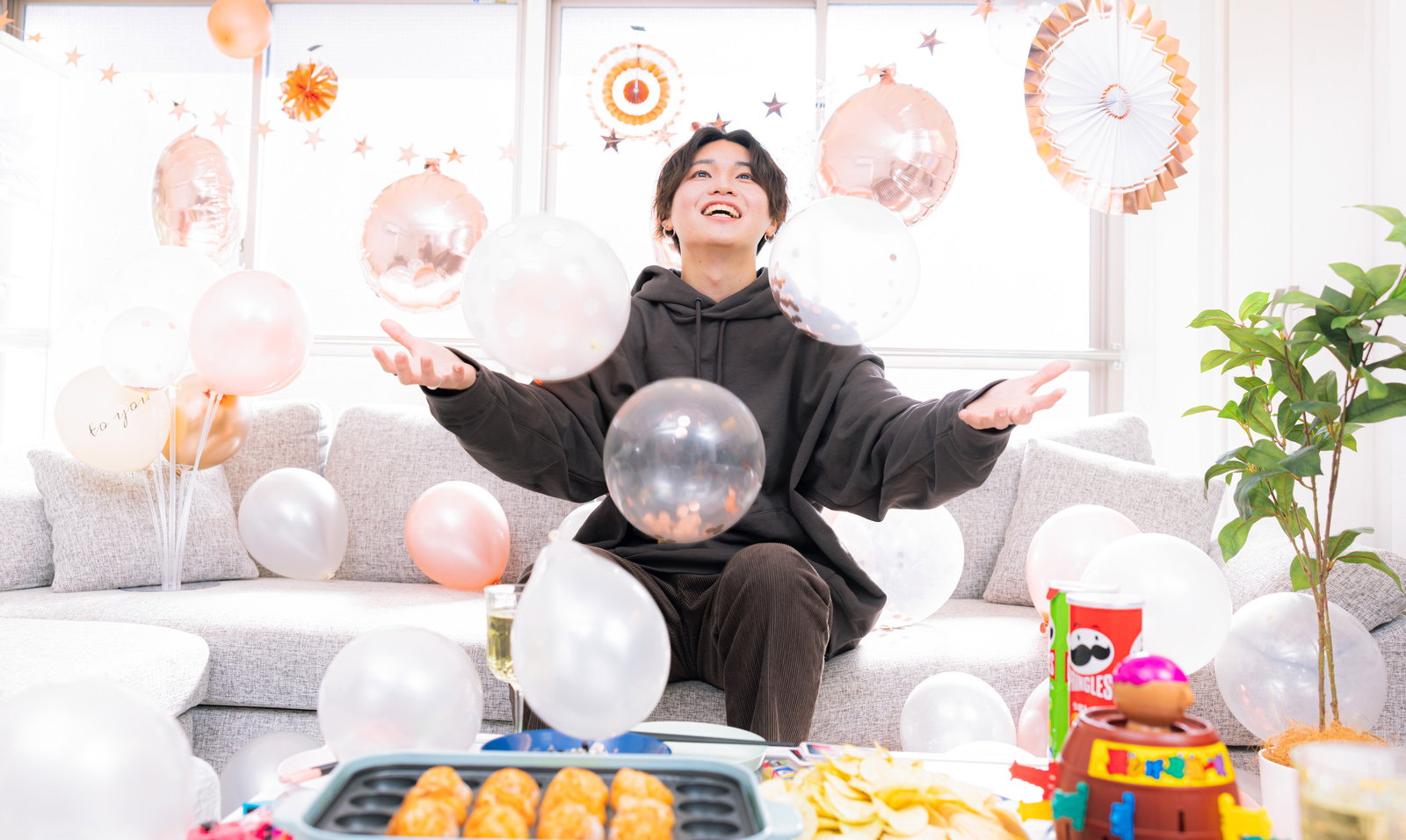 たこ焼き器を前に両手を広げて喜ぶ男性のホームパーティー風景［モデル：SHUN］