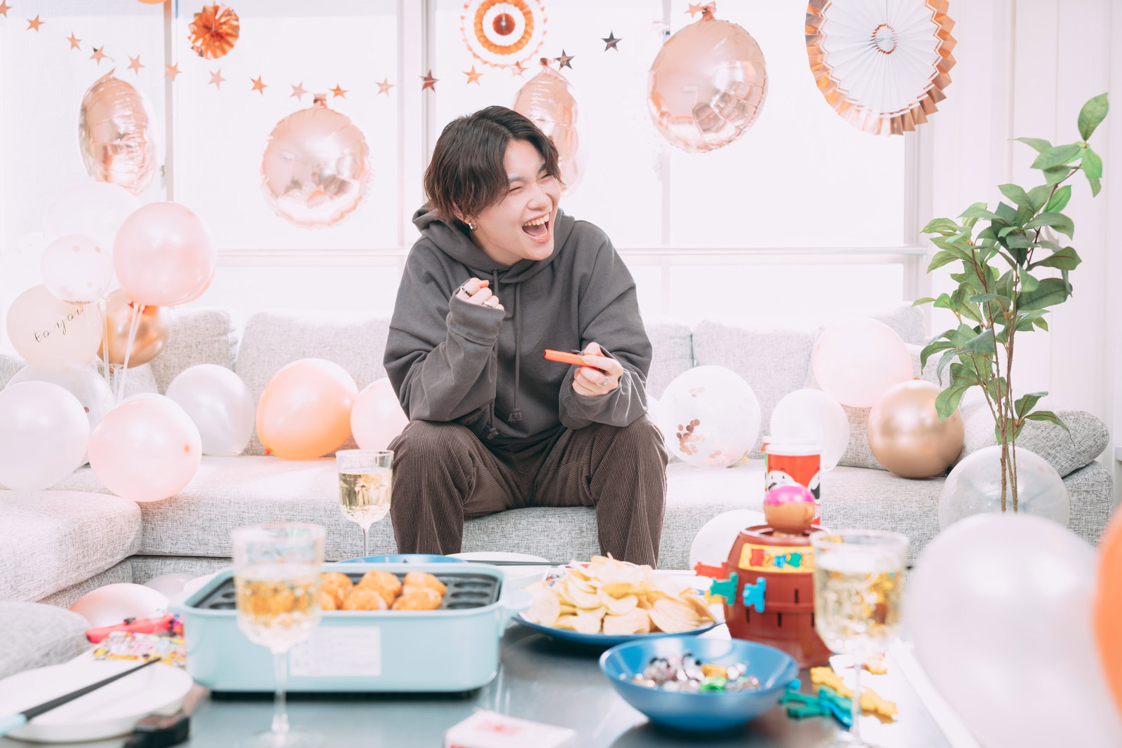 ゲームで勝利してガッツポーズをとる男性とパーティーグッズ［モデル：SHUN］