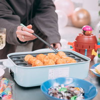 ホットプレートを囲んでタコパしてる様子、友人たちの楽しい食事風景の写真