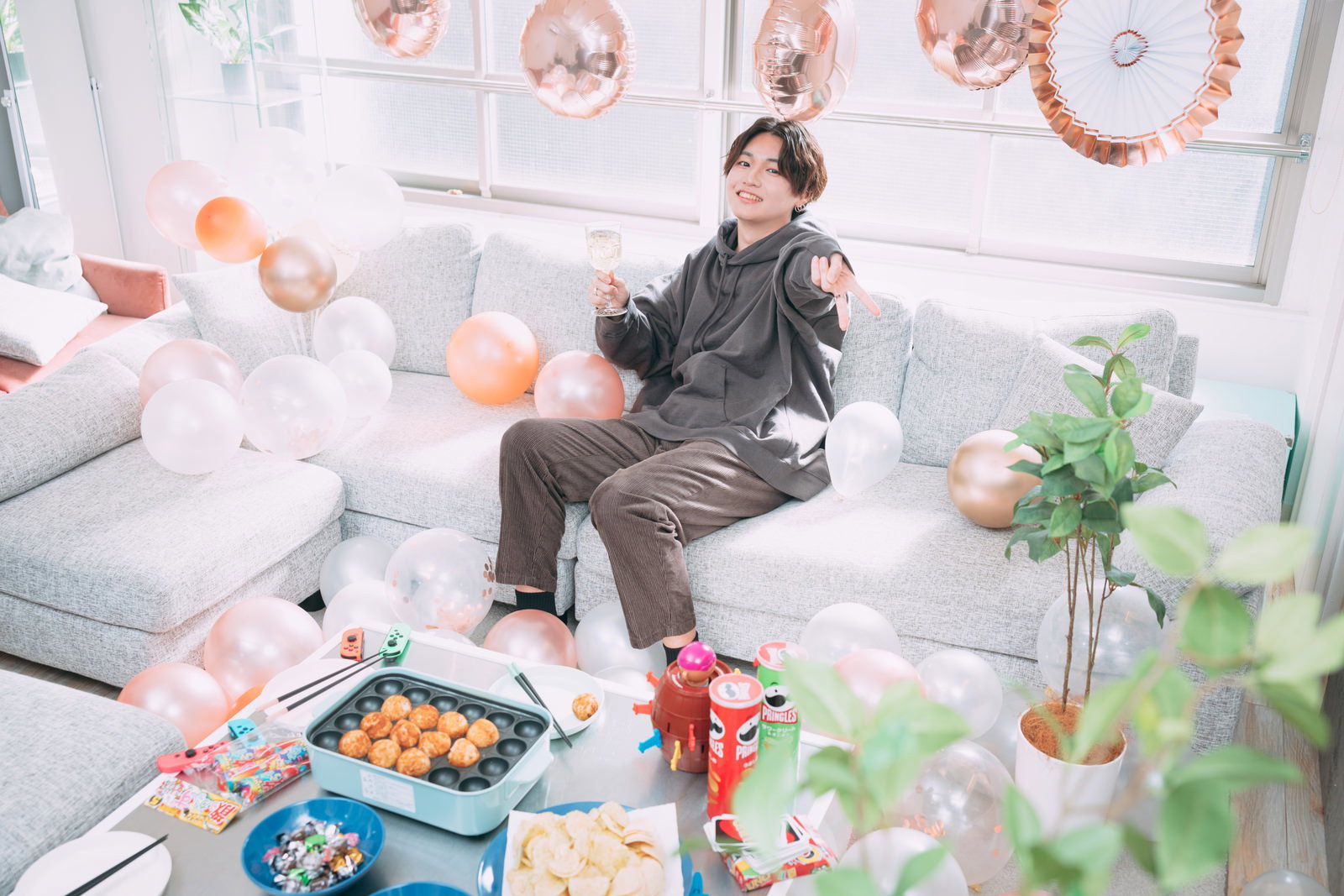 ホームパーティでピースサインをする笑顔の男性［モデル：SHUN］