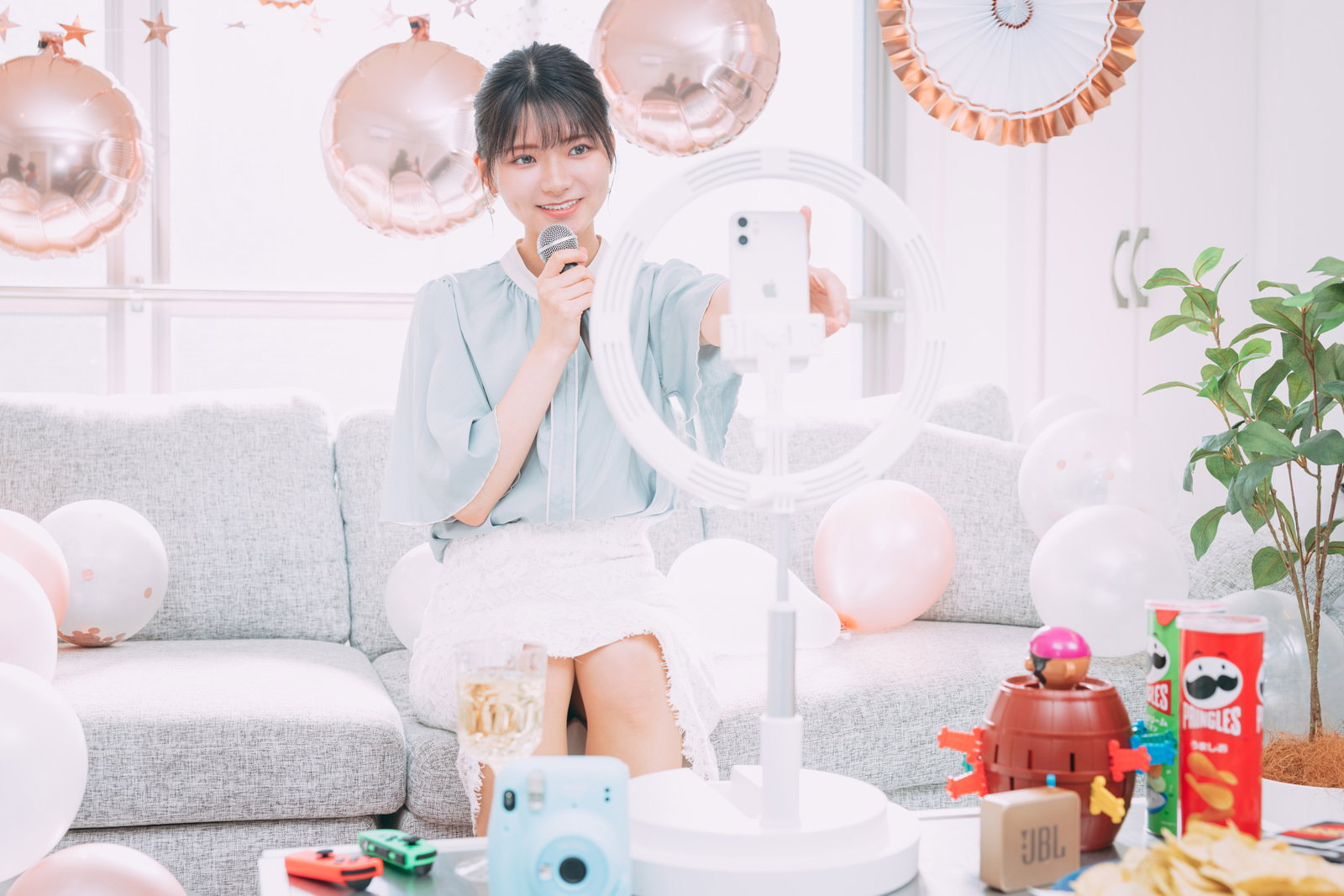 パーティー装飾のある室内でスマートフォンを使って生配信をする女性［モデル：モデルリリース］