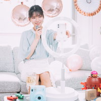 ホームパーティーの会場でスマートフォンを使って生配信する女性の写真
