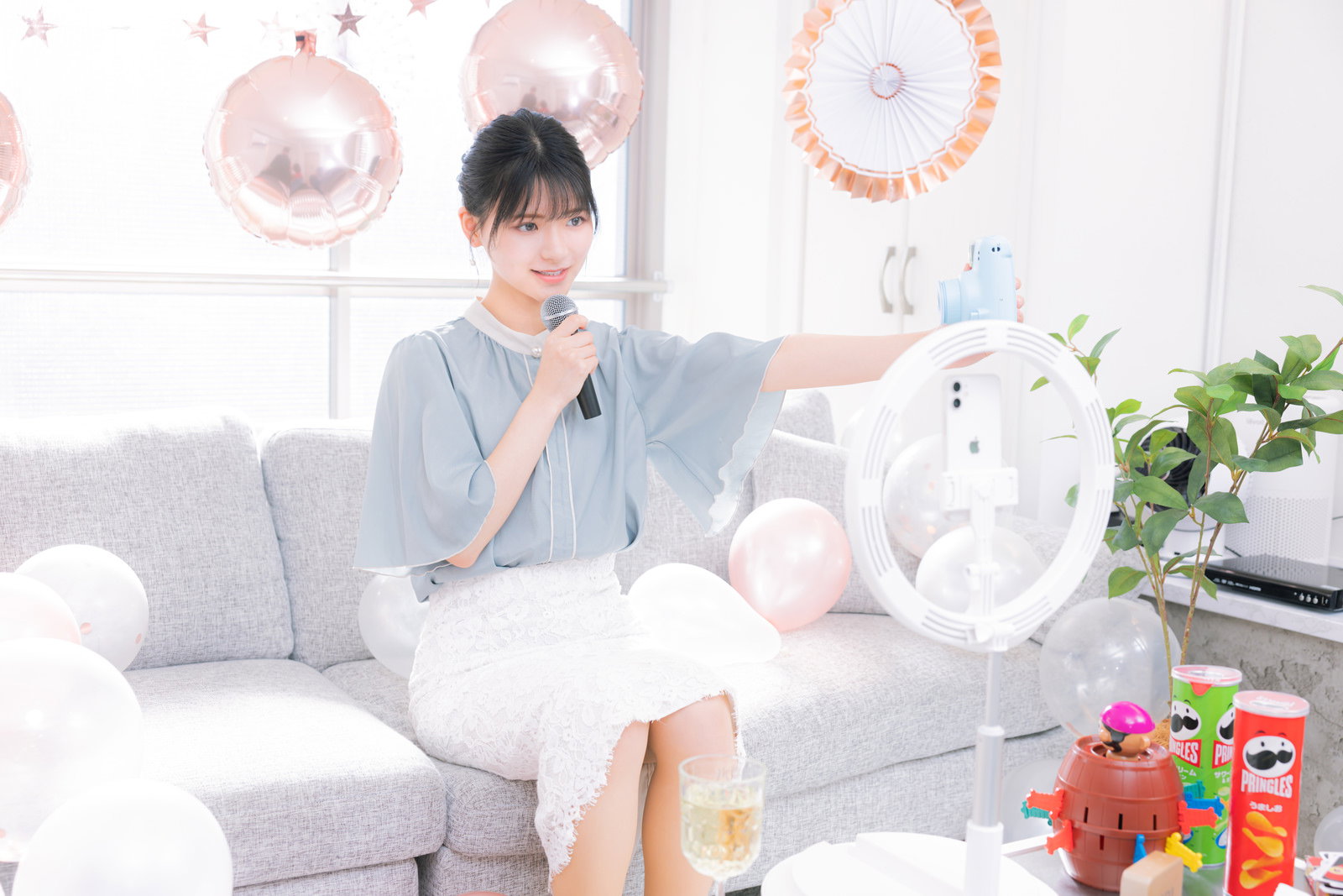 スマートフォンで自撮りしながら記念配信する笑顔の女性ライバー［モデル：モデルリリース］