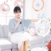 スマートフォンで自撮りしながら生配信する記念放送の女性ライバーの写真
