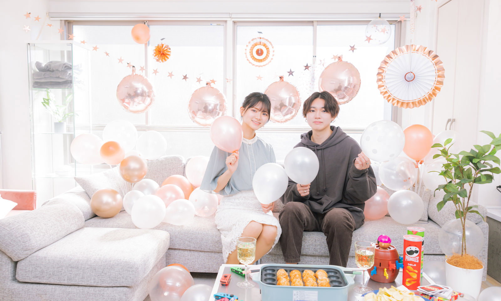 記念日にソファでシャンパンで乾杯する恋人とパーティー装飾［モデル：モデルリリース SHUN］