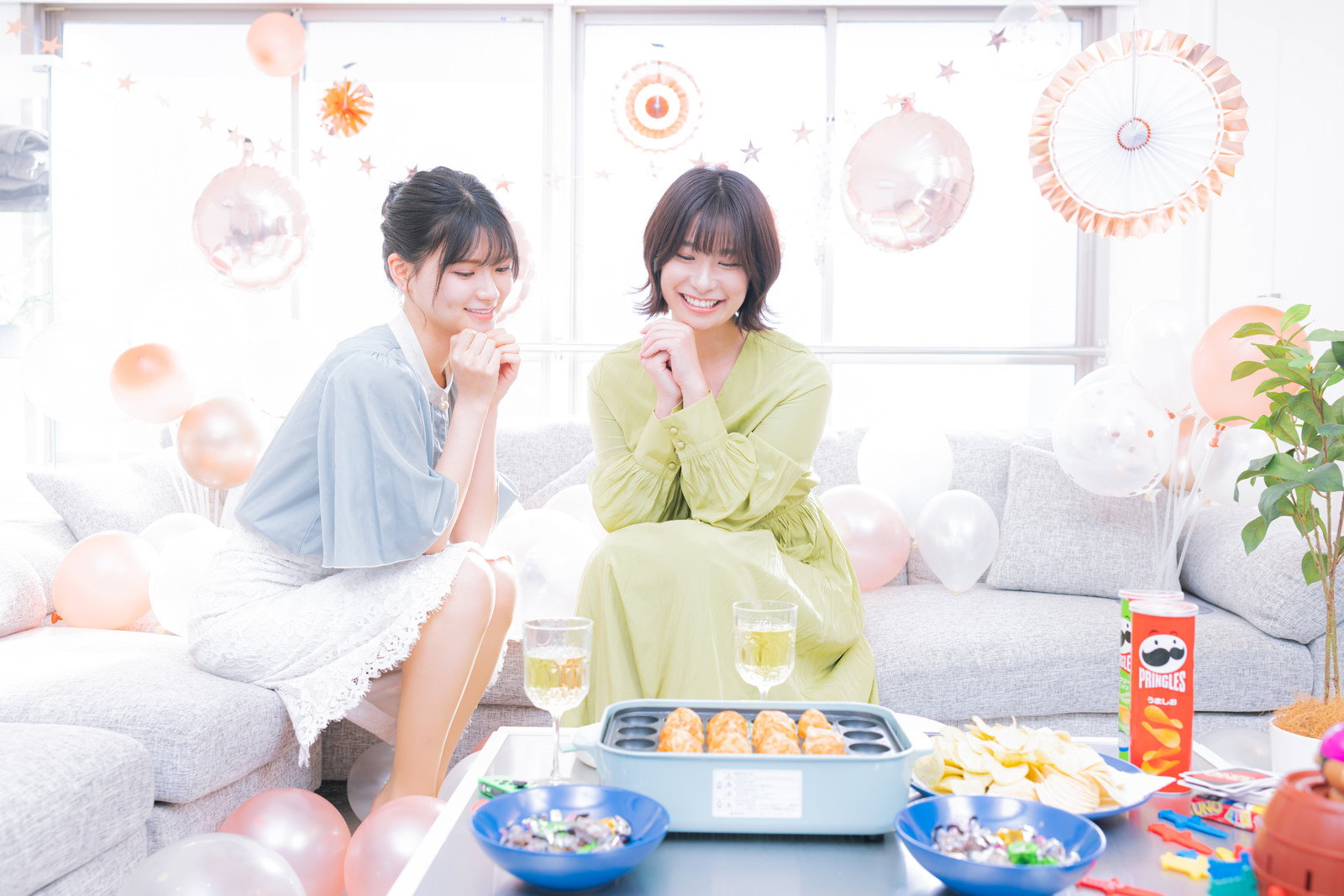 たこ焼きプレートを囲んでパーティーを楽しむ女性二人［モデル：夏実 モデルリリース］