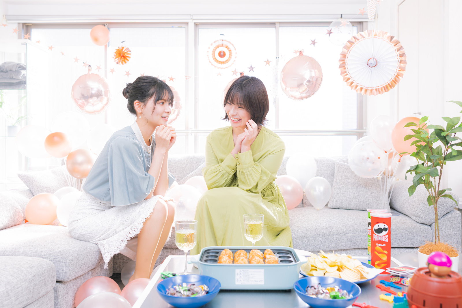 リビングでたこ焼き器を囲みながら楽しく会話する女性2人［モデル：モデルリリース 夏実］