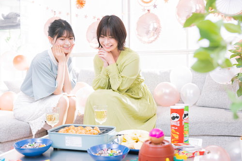 緑と薄いブルーのトップスの女性二人がシャンパンで乾杯するホームパーティー