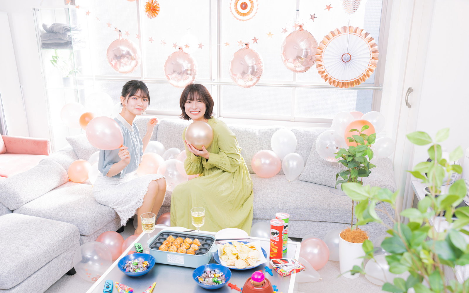 ソファに座りシャンパンで乾杯するホームパーティーの女性［モデル：モデルリリース 夏実］