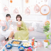 ホームパーティーで乾杯して喜ぶ女性たちとテーブルの料理の写真