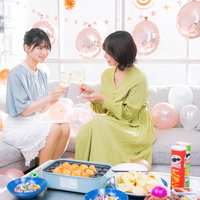 ホームパーティーで乾杯するシャンパングラスを合わせる女子ふたりの写真
