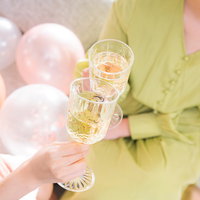 シャンパングラスで乾杯する黄緑色の服を着た女性の手元の写真