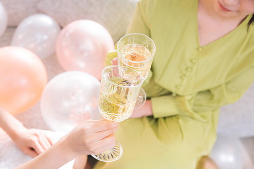 シャンパングラスで乾杯する黄緑色の服を着た女性の手元