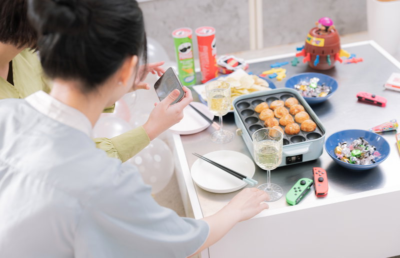 たこ焼きパーティーの様子を撮影する女子の写真