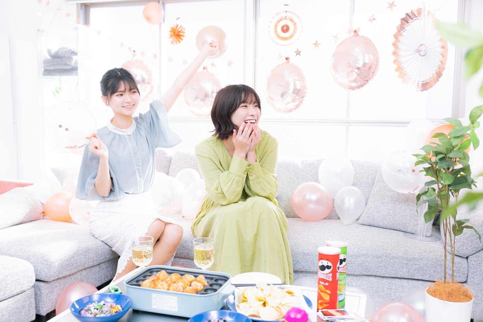ソファで推しの映像を見て盛り上がる女性たちの女子会風景［モデル：モデルリリース 夏実］