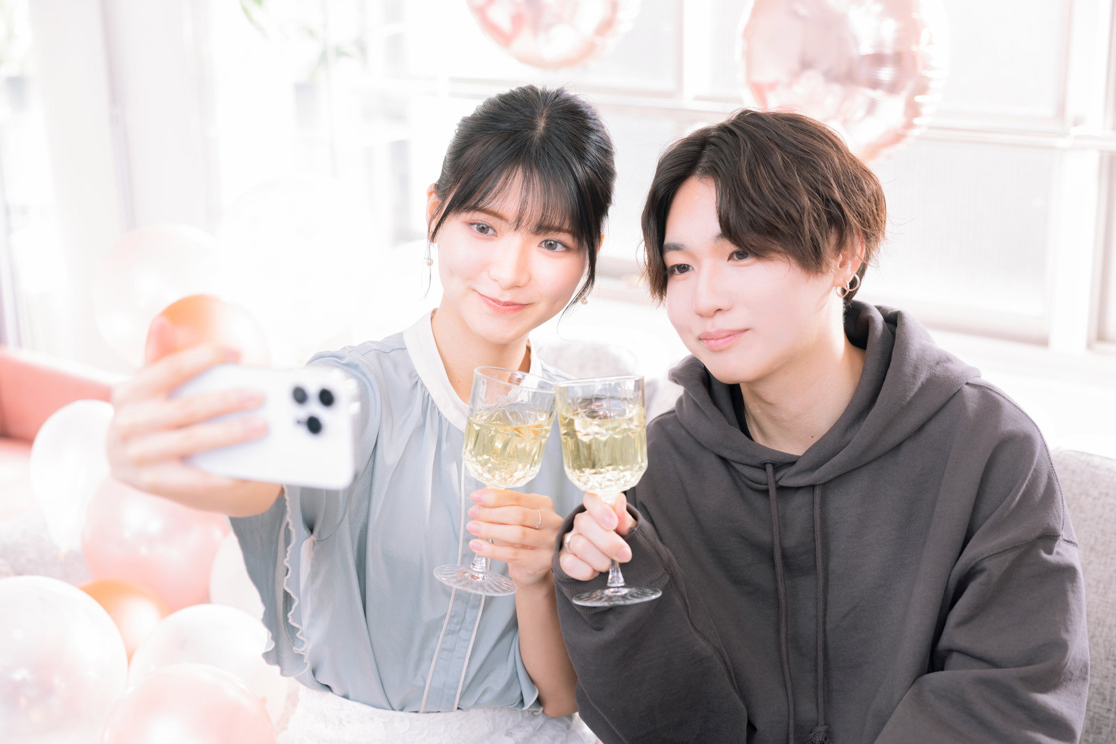 記念日にシャンパングラスを持って乾杯する男性と女性のカップルが自撮りしている様子［モデル：SHUN モデルリリース］