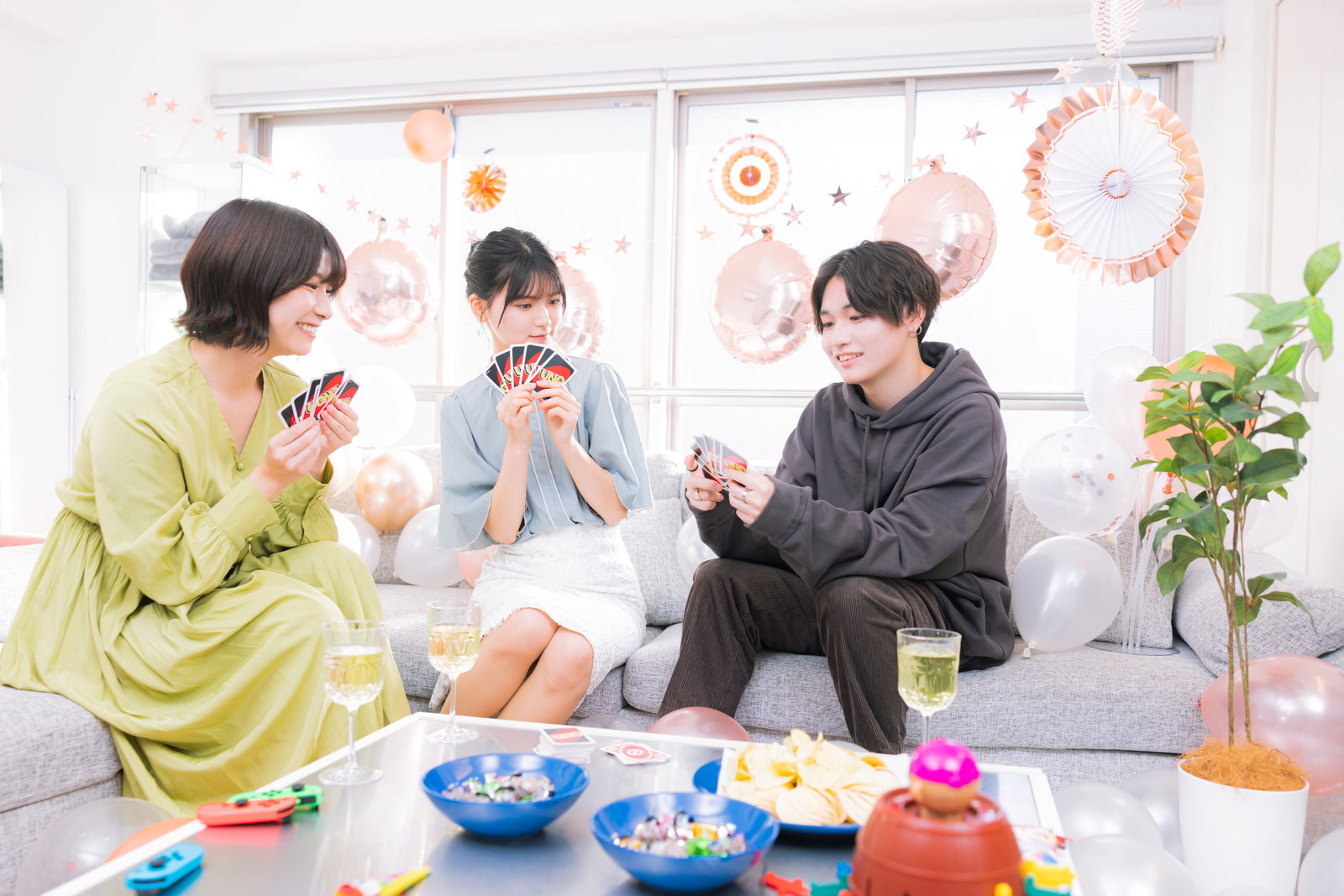 ホームパーティーでUNOをする男女3人［モデル：モデルリリース 夏実 SHUN］