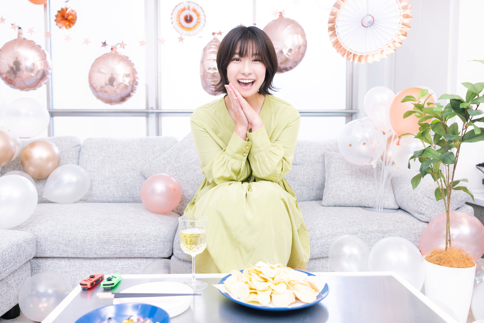 黄色いトップスを着た女性が明るい室内で満面の笑顔で会話している［モデル：夏実］