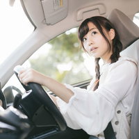 目視で後方を確認する若い女性ドライバーの安全運転の写真