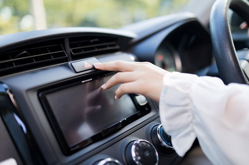 ハザードランプ（非常点滅表示灯）を押す運転席の手