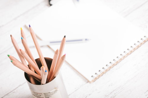 白い背景に配置した木製の鉛筆立てとノート