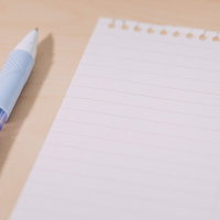 木製デスクに置かれた白い便箋とペン、手紙作成シーンの写真