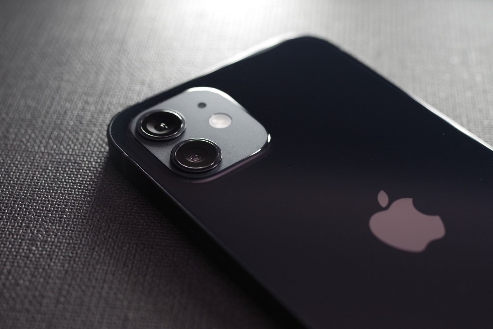 黒いiPhone12の背面に配置されたデュアルレンズカメラとAppleロゴ