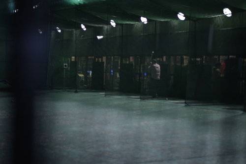 深夜のバッティングセンター、ネット越しに見える照明と練習場