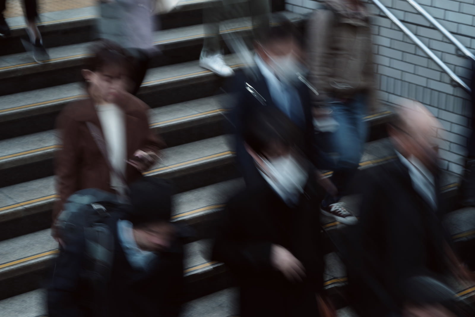 通勤ラッシュ時の駅ホーム階段を下る人々のモーションブラー