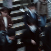 通勤時間帯の駅ホームの下り階段を行き交う人々の写真